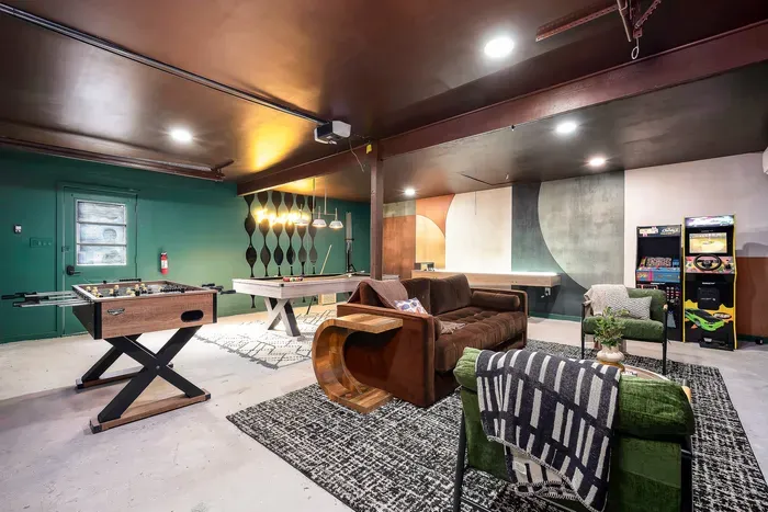 Stylish game room with pool, foosball, arcade games, and cozy lounge seating