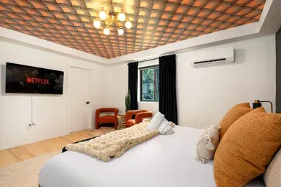Stylish bedroom with designer ceiling, TV, AC, and cozy seating nook