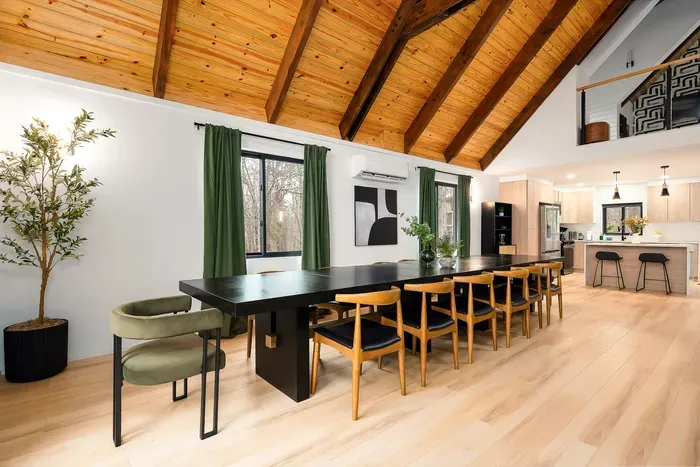 Vaulted wood ceilings, spacious dining table, and a sleek modern kitchen