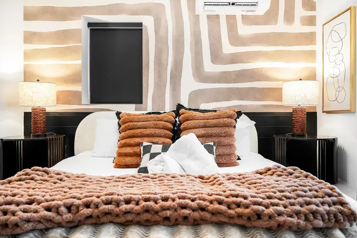 Designer bedroom with bold mural, cozy knit throw, and modern comforts