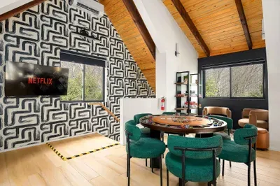 Modern game loft with poker table, TV, and bright wooded views