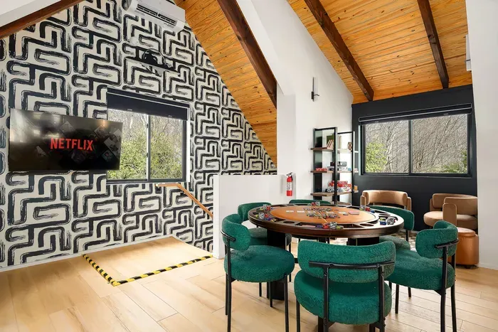 Modern game loft with poker table, TV, and bright wooded views