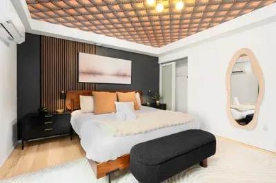 Boutique-style bedroom with designer ceiling, plush bed, and sleek modern accents