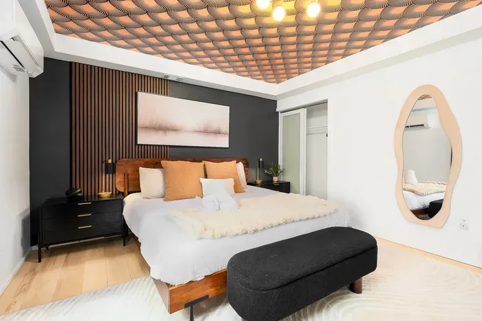Boutique-style bedroom with designer ceiling, plush bed, and sleek modern accents