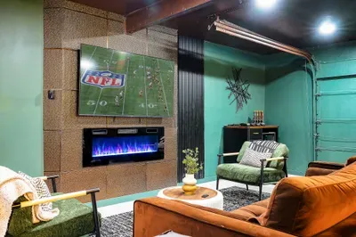 Modern game-day lounge with big-screen TV, fireplace, and cozy seating
