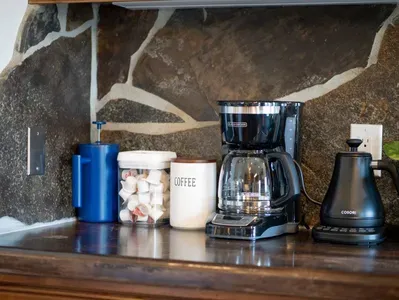 Coffee Bar includes ground coffee, coffee maker, French press, hot water kettle, and coffee creamer.