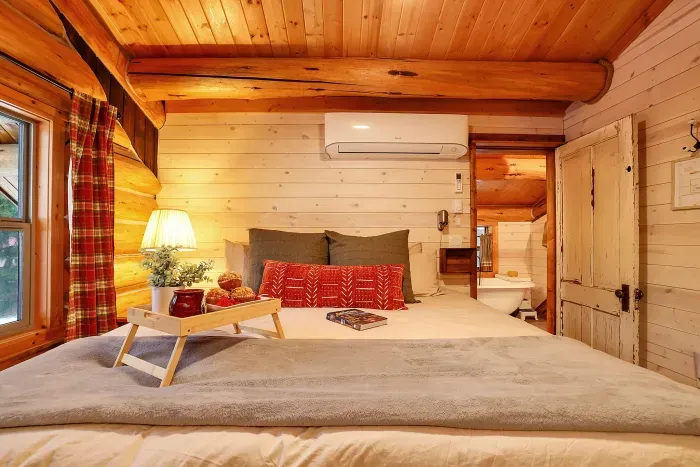 Your primary bedroom feels like a classic cabin loft—hand‑hewn beams, vaulted ceiling, and a king bed made for deep mountain sleep. Ensuite bath is super charming with dual copper sinks, a claw foot tub, and a walk-in shower