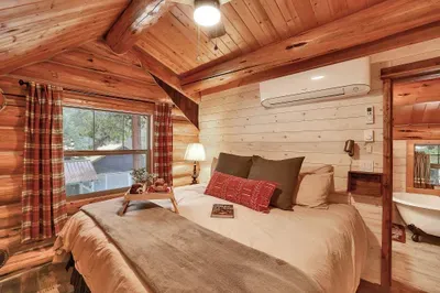 From the king bed, you can see the beams, feel the quiet of the pines outside, and know you’re in a true log cabin, not a copy. The mini-split offers the comfort of AC in the summertime