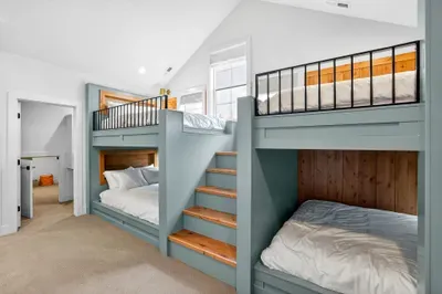 Built-in nooks, individual lighting, and sturdy construction give the bunk room a classic summer-camp-meets-inn charm.