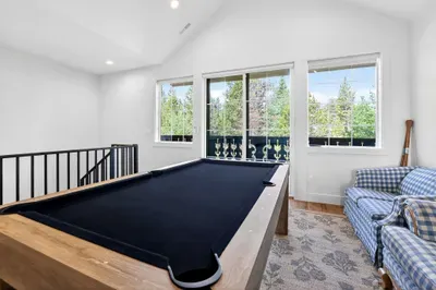 The game loft is located just off the bunk room and queen bedrooms, making it a natural gathering point for kids and teens. Upper balcony off the second-floor landing offers a quieter outdoor perch—perfect for a book and a glass of wine