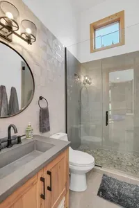 The upstairs full bath has an extra long vanity and an expansive walk-in shower, also with beautiful river rock tile