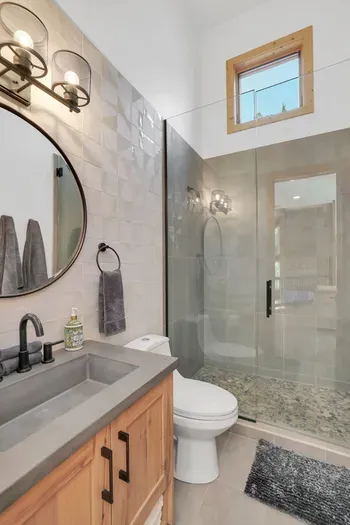The upstairs full bath has an extra long vanity and an expansive walk-in shower, also with beautiful river rock tile