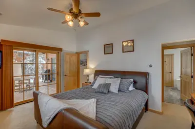 The main-floor primary suite, complete with king-sized bed, access to the back patio, a remodeled ensuite bathroom, and a dedicated work space