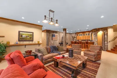 Downstairs, the living room anchors the evening—wood‑burning hearth, deep seating, and doors that open to the spa and fire pit