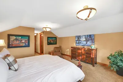 Upstairs king suite with calm mountain light, crisp linens, walk-in closet, and a bath that pairs a dual vanity with a simple, family‑friendly shower/tub combo