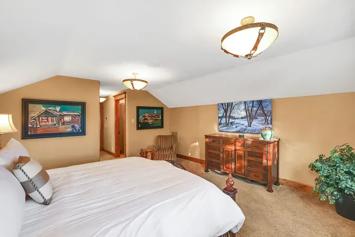 Upstairs king suite with calm mountain light, crisp linens, walk-in closet, and a bath that pairs a dual vanity with a simple, family‑friendly shower/tub combo