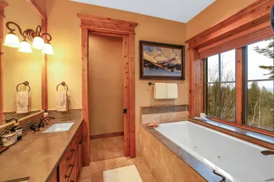 The ensuite pairs a deep soaking tub with a view of the pines, turning evenings into a quiet ritual