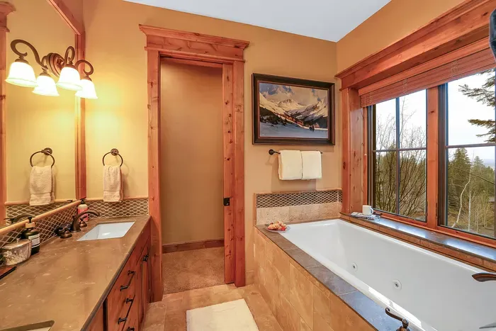 The ensuite pairs a deep soaking tub with a view of the pines, turning evenings into a quiet ritual