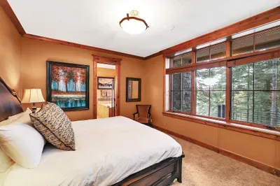 The first downstairs king guest suite is calm and grounded—mountain views framed by glass and a bed that invites real rest