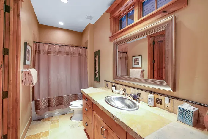 The ensuite’s shower/tub combo keeps routines easy; crack the patio door for cool mountain air and slip straight to the built‑in stone spa