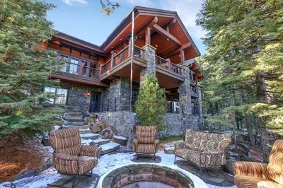 Expansive outdoor living on two levels—wraparound deck above, stone patio below, with hot tub, dual fire pits, grills, and enough seating to keep the whole group outside until the stars come out