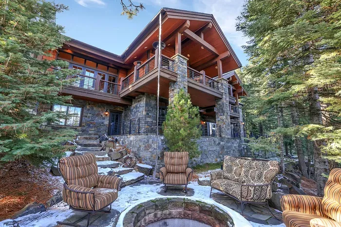 Expansive outdoor living on two levels—wraparound deck above, stone patio below, with hot tub, dual fire pits, grills, and enough seating to keep the whole group outside until the stars come out