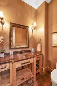 Warm wood, hammered copper, and refined fixtures make the upstairs powder room a quiet pause between gatherings—simple, elegant, and perfectly on pace with the lodge