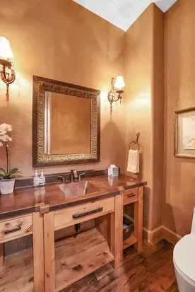 Warm wood, hammered copper, and refined fixtures make the upstairs powder room a quiet pause between gatherings—simple, elegant, and perfectly on pace with the lodge