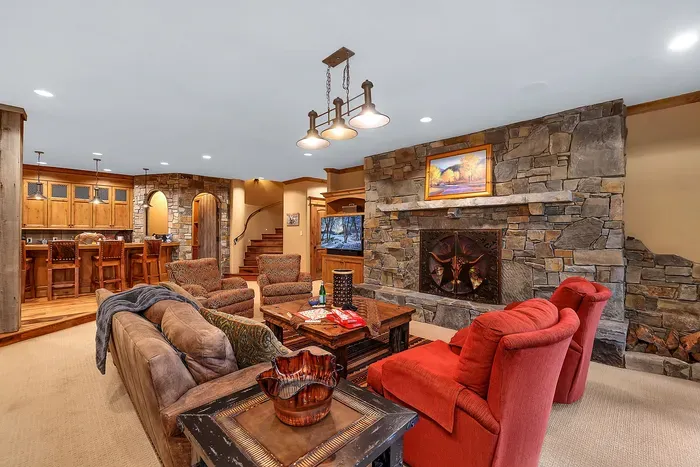 The downstairs living room is where evenings land—wood‑burning hearth, deep seating, and doors that open to the spa and fire pit