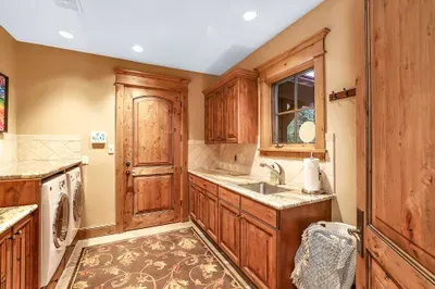 The main‑floor laundry and mudroom keep the day moving—hooks and benches for gear, sturdy cabinetry, and one of three washer/dryer sets for quick turnarounds between runs