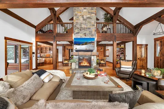 Where everyone actually hangs out: a warm, modern living room with a dual-sided gas fireplace, big windows, and plenty of space to sink in after a full day outside