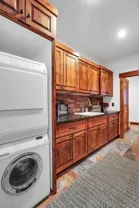 The spacious laundry room offers a stackable washer and dryer, utility sink, and plenty of storage and counter space.