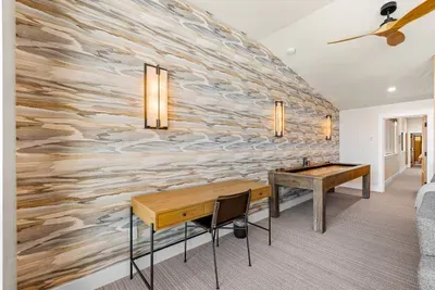 Second‑floor lounge with shuffleboard, wet bar, and workspace