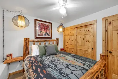 This queen bedroom not only boasts a charming log frame bed but also offers a spacious closet with built-in shelving
