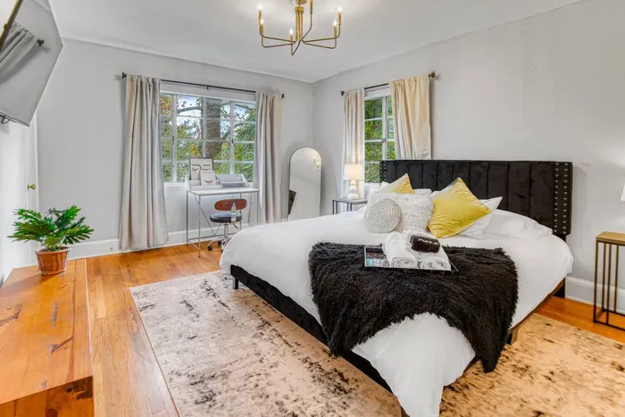 Bright, modern bedroom with a cozy bed, workspace by the window, and smart TV — designed for comfort and productivity.