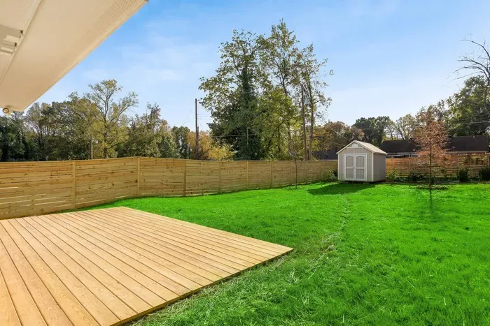 "Relax or entertain in the spacious fenced backyard featuring a large wooden deck and lush green lawn