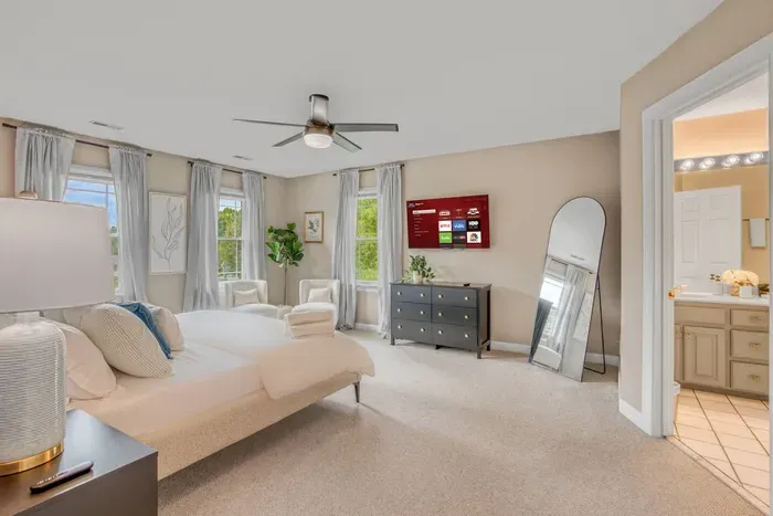 A 43-inch Smart TV sits on top of the dresser in the Primary Bedroom. The open door on the right leads to the Primary Bathroom.