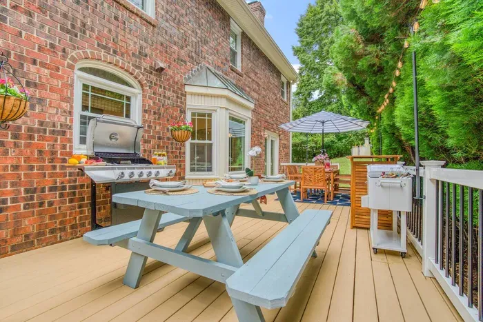 Charming outdoor dining deck featuring a grill, picnic-style table, and shaded seating area — perfect for barbecues, alfresco meals, and relaxing gatherings under the string lights.