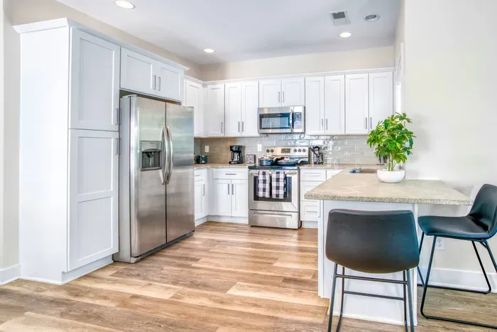 Bright, fully equipped kitchen with stainless steel appliances, modern finishes, and a cozy breakfast bar.