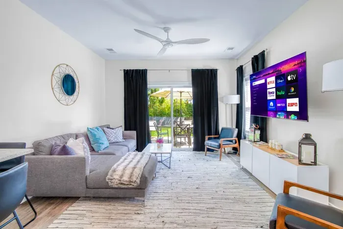 Bright and modern living room with cozy seating, smart TV, and patio access for relaxing indoor-outdoor living.