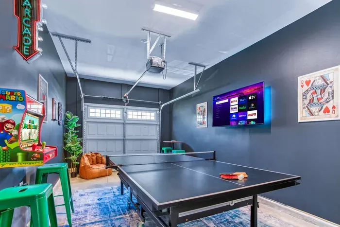 Enjoy endless fun in this vibrant game room featuring a ping pong table, retro Super Mario arcade machine, wall-mounted dartboard, and a large smart TV.