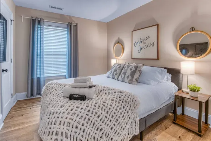 Queen bedroom with plenty of pillows, a thick duvet cover, two nightstands and a 40" Roku TV.