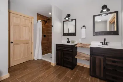 Spacious dual sinks, rustic mirrors, and wood shelving—plus a beautifully tiled stand-up shower for a spa-like feel. ✨