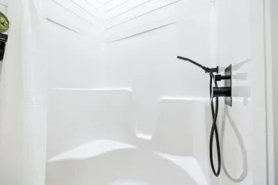 This basement bathroom stand-up shower features a sleek design with a rain shower head (not shown) plus a handheld shower, perfect for relaxing after a long day.