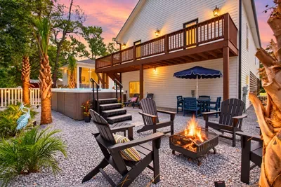 Your own coastal backyard retreat—soak in the swim spa, relax fireside under the palms, and make the most of warm Oak Island evenings at Sea Glass Serenity on 75th!