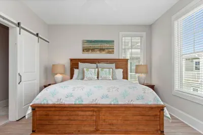 Coastal elegance meets comfort!  This master king suite features a plush bed and a sleek white sliding barn door leading to your private ensuite bathroom.