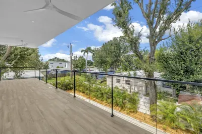 Spacious covered balcony with glass railing and peaceful tree-lined views