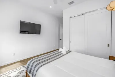 Bright modern bedroom with TV, cozy bed, and spacious closet