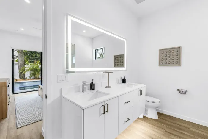 Spa-like double vanity bath with glowing mirror and poolside access