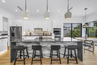 Bright designer kitchen with marble island, bar seating, and dining nook